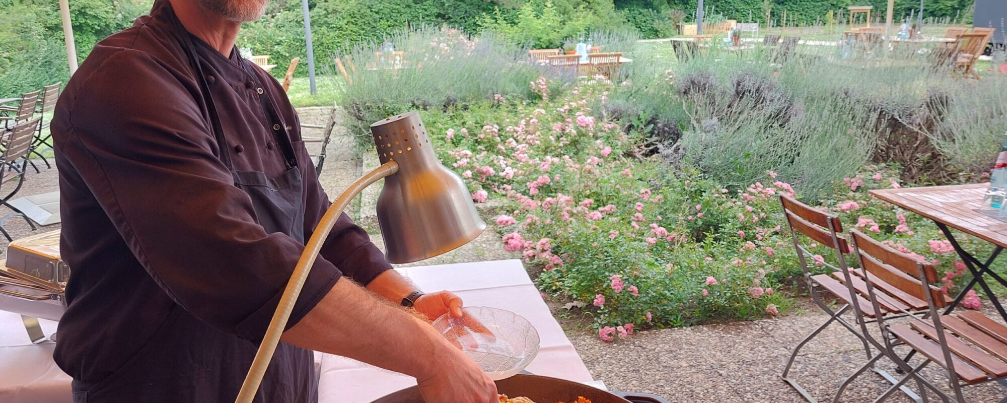 Koch mit einer großen Schale Paella auf der Terrasse