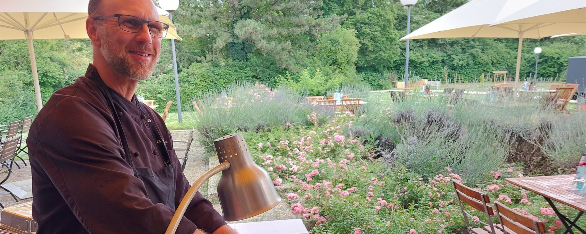 Koch mit einer großen Schale Paella auf der Terrasse