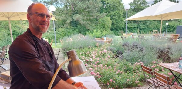 Koch mit einer großen Schale Paella auf der Terrasse